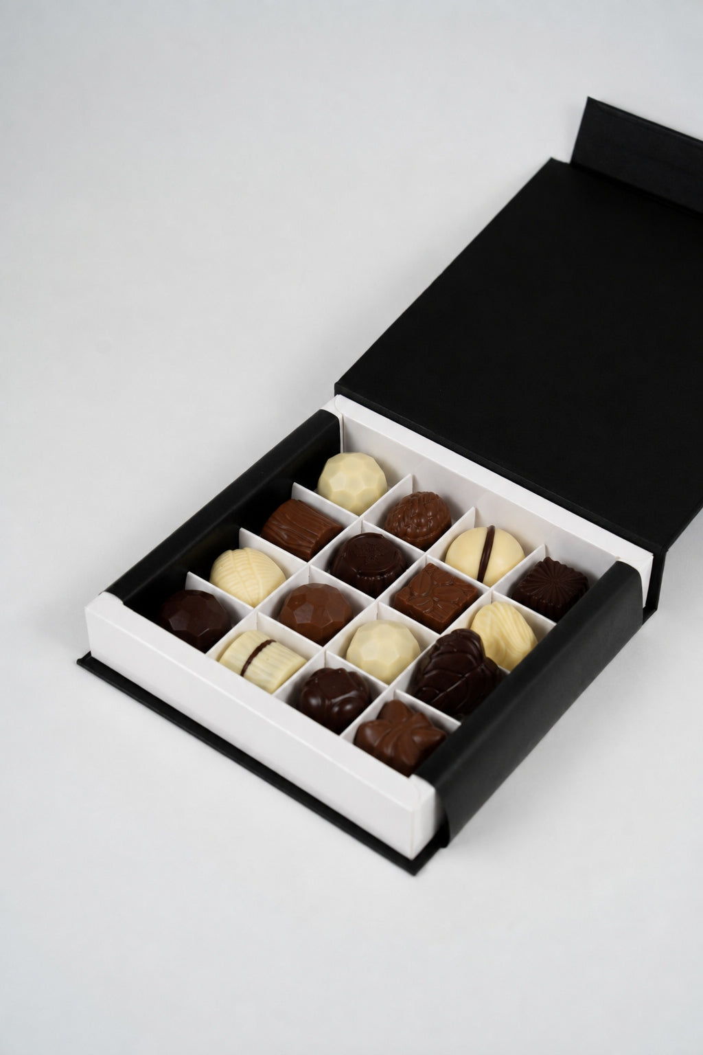 Coffret noir ouvert de 200 g avec 16 pralines belges assorties