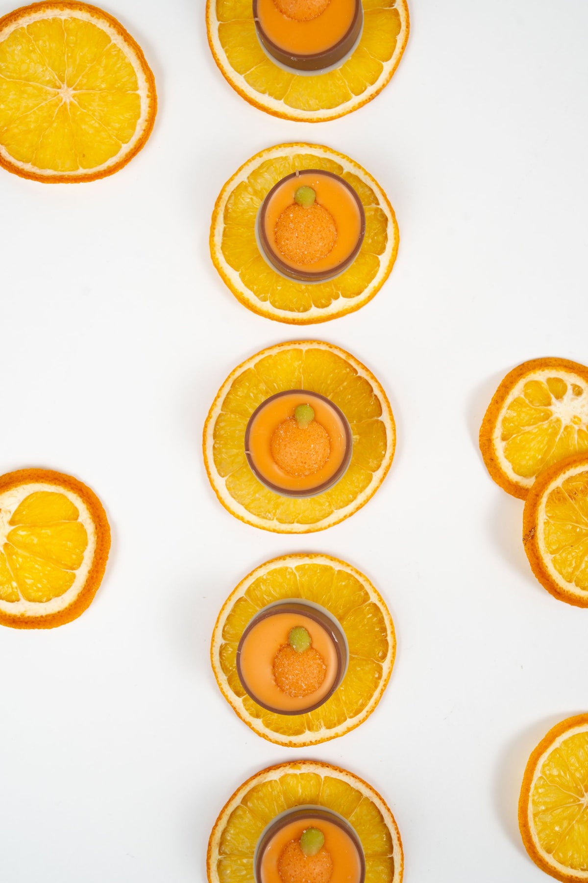 Copas de chocolate belga rellenas de ganache de naranja, servidas sobre rodajas de naranja