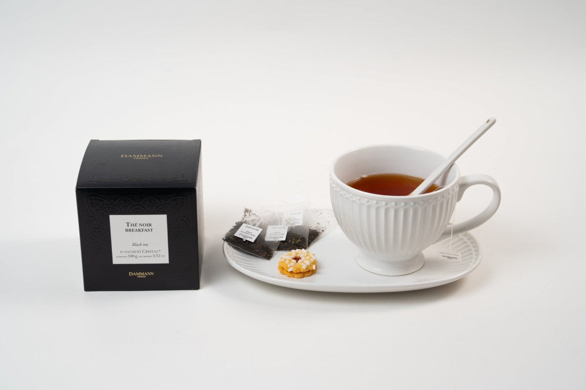 Dammann Frères Breakfast black tea with cup, tea sachets and biscuit on plate.