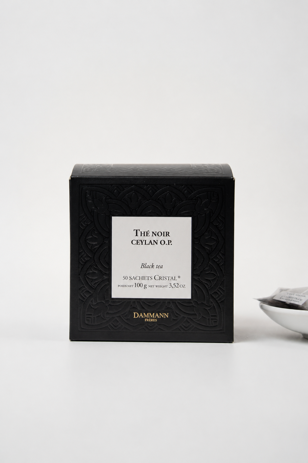 Dammann Frères Ceylan O.P. black tea in elegant luxury French tea packaging with minimalist editorial styling and tea sachets in the background