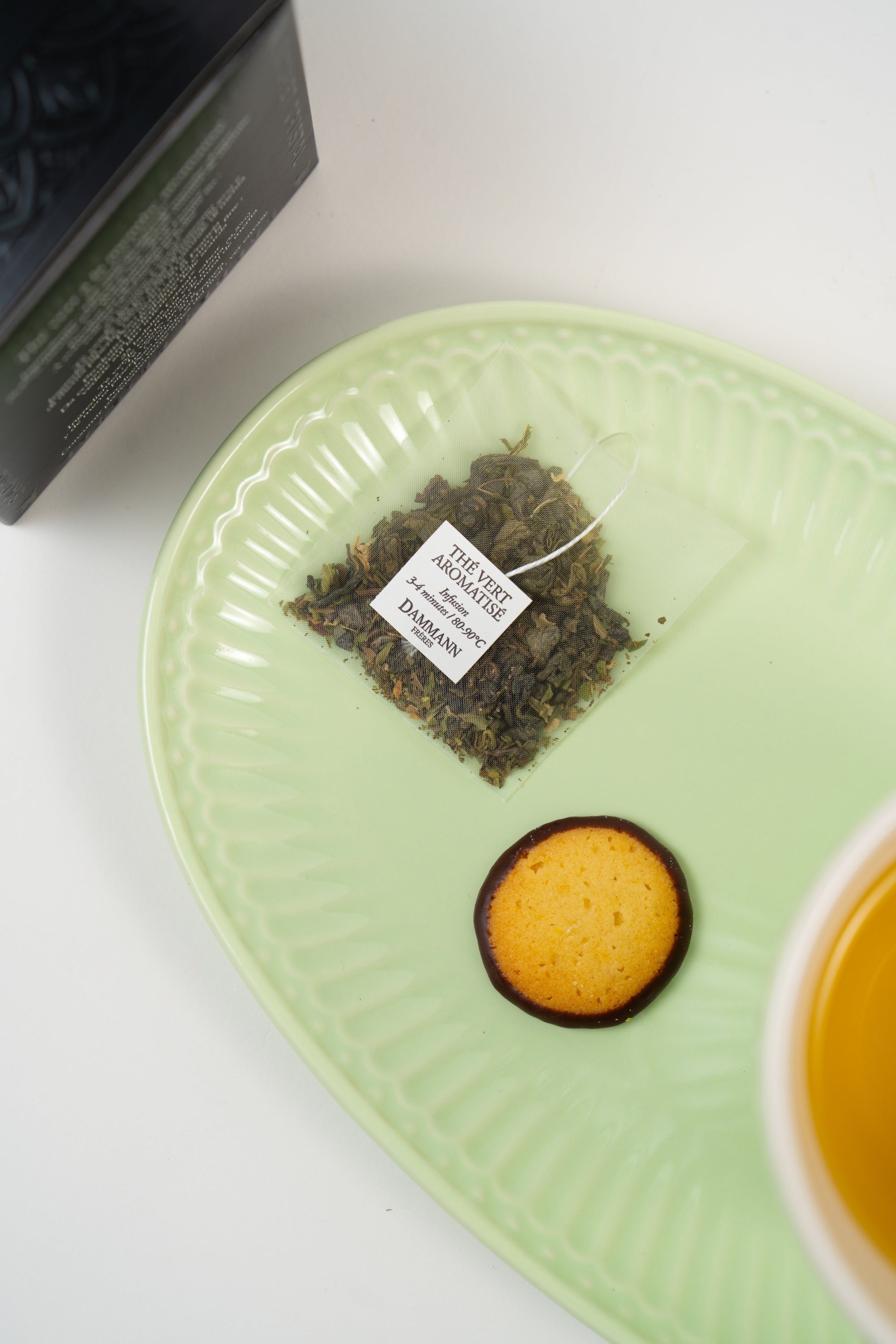 Dammann Frères mint green tea sachet served with brewed green tea and delicate biscuit on pastel green porcelain