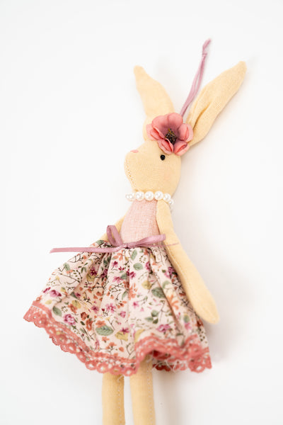 Decorative fabric rabbit soft toy wearing a floral dress with pink details and pearl necklace