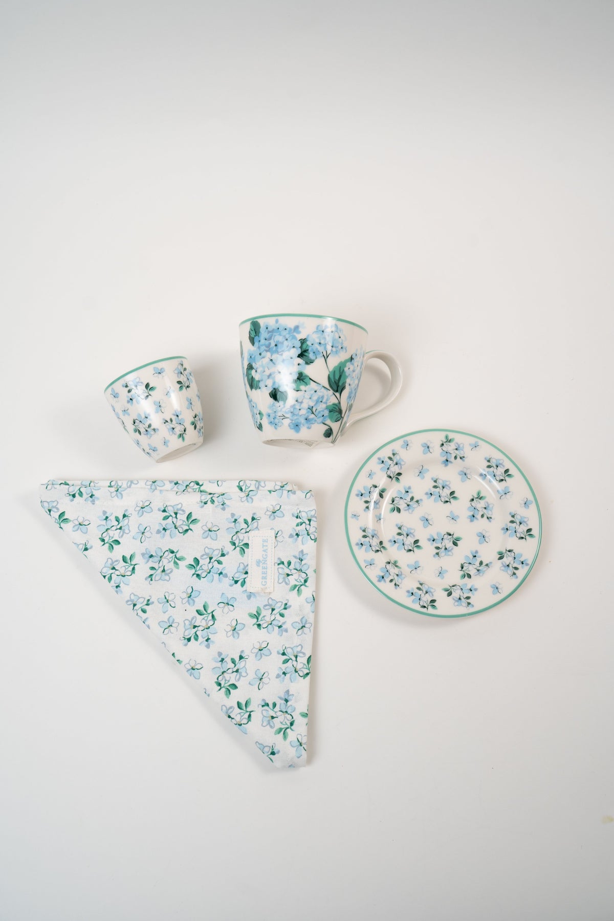 GreenGate Liliana floral tableware collection featuring a ceramic mug, espresso cup, plate and matching floral napkin in soft blue tones