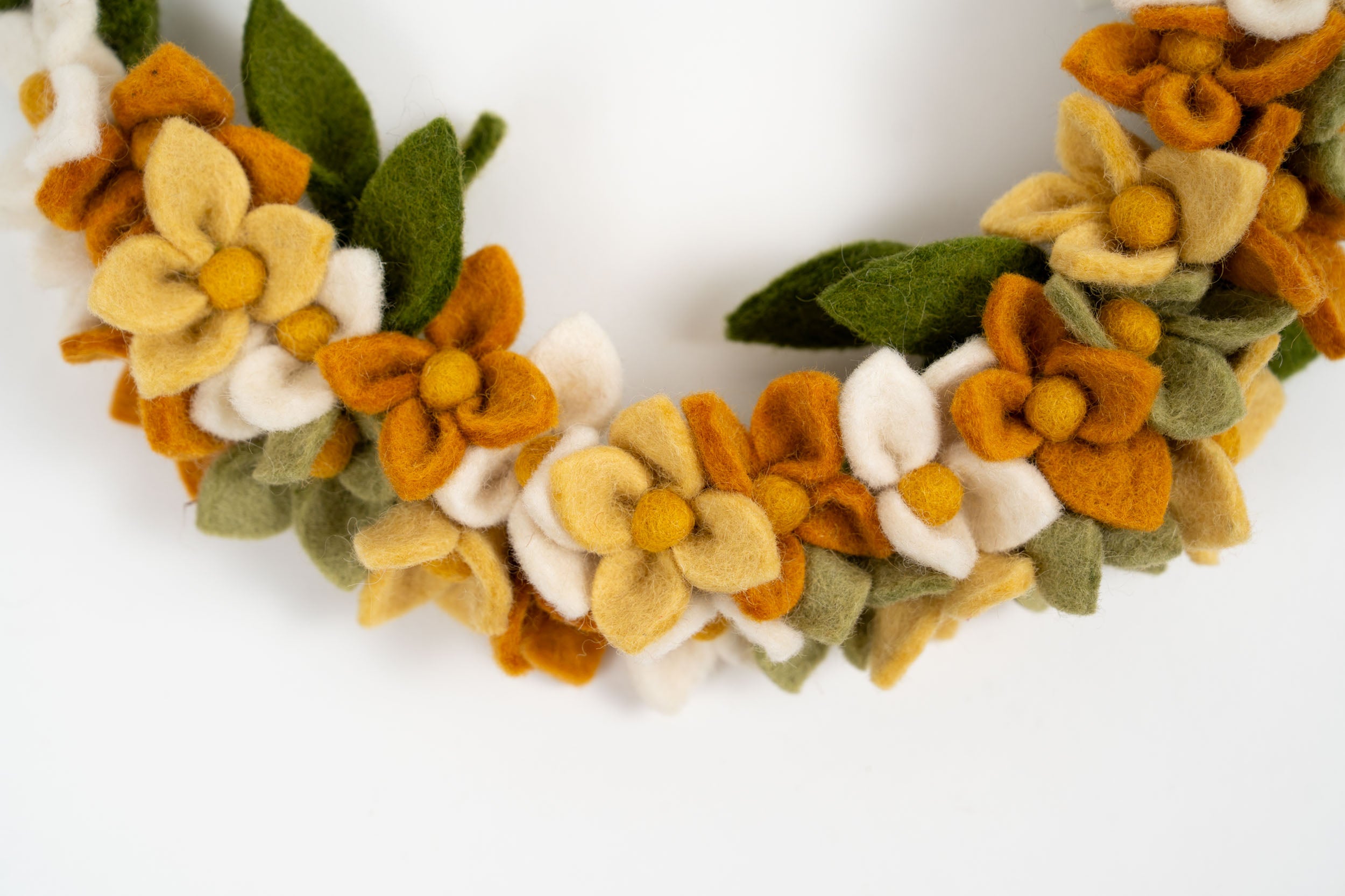 Close-up of a Gry & Sif felt floral wreath with soft yellow, white, and green handmade flowers.