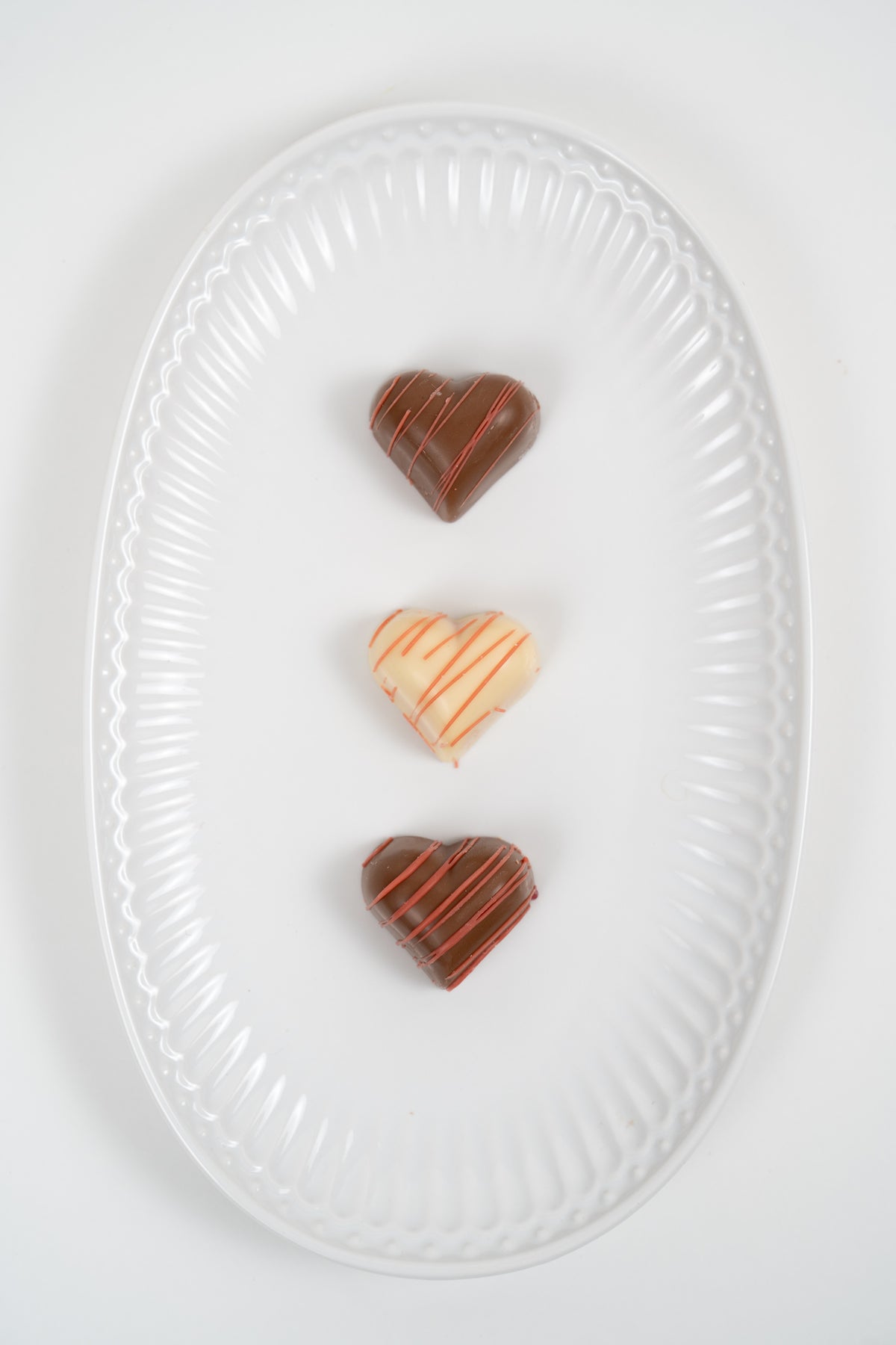 Heart shaped filled chocolates in milk and white chocolate on plate