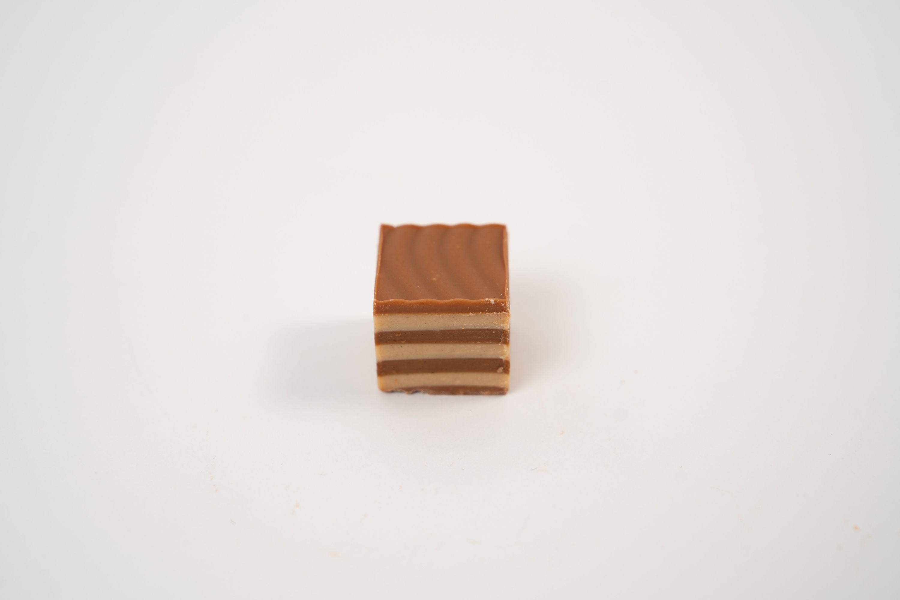 Layered hazelnut nougat praline with light and dark nougat layers.