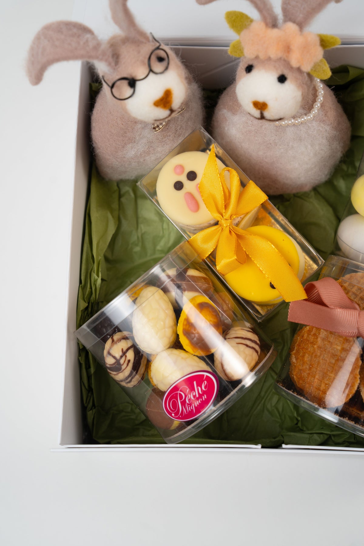 Gros plan sur des macarons artisanaux décorés en forme de lapins blancs, fourrés à la crème stracciatella pour la collection Univers de Pâques.