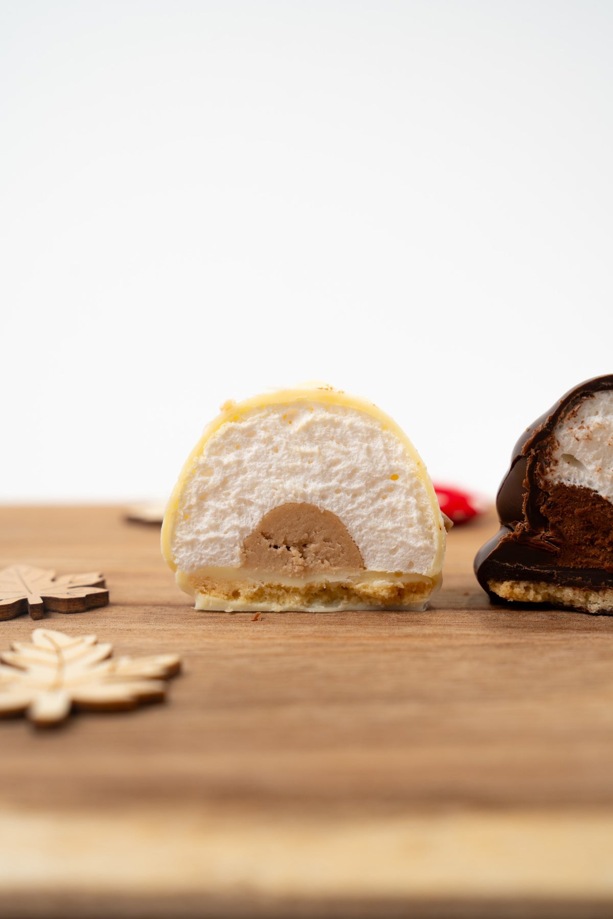 Melocake au chocolat blanc coupé en deux, révélant une guimauve moelleuse, un cœur fondant Kinder Bueno et une base biscuitée, présenté sur une planche en bois.