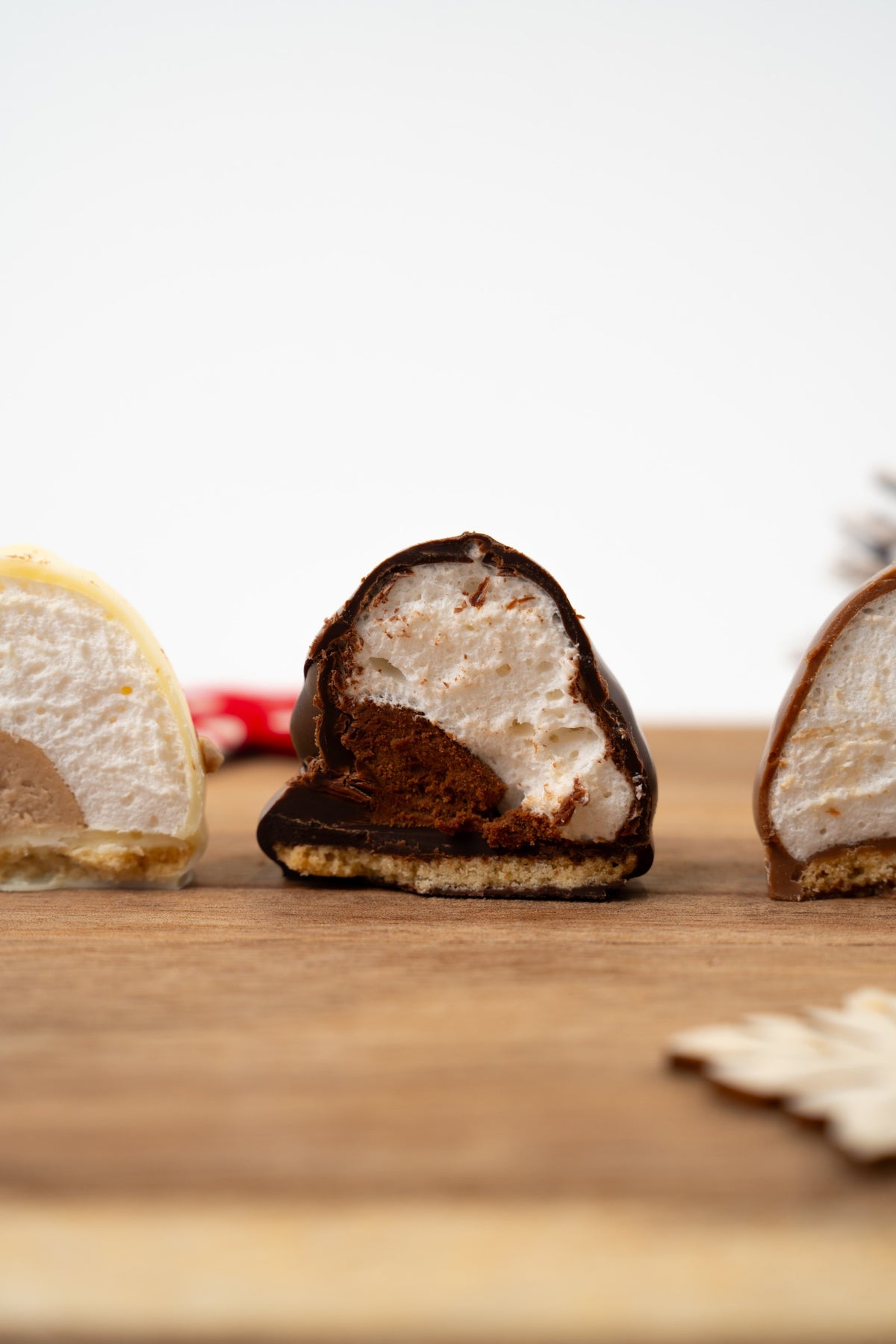 Melocake au chocolat noir coupé en deux, révélant une guimauve moelleuse, un cœur de mousse au chocolat et une base biscuitée, présenté sur une planche en bois.