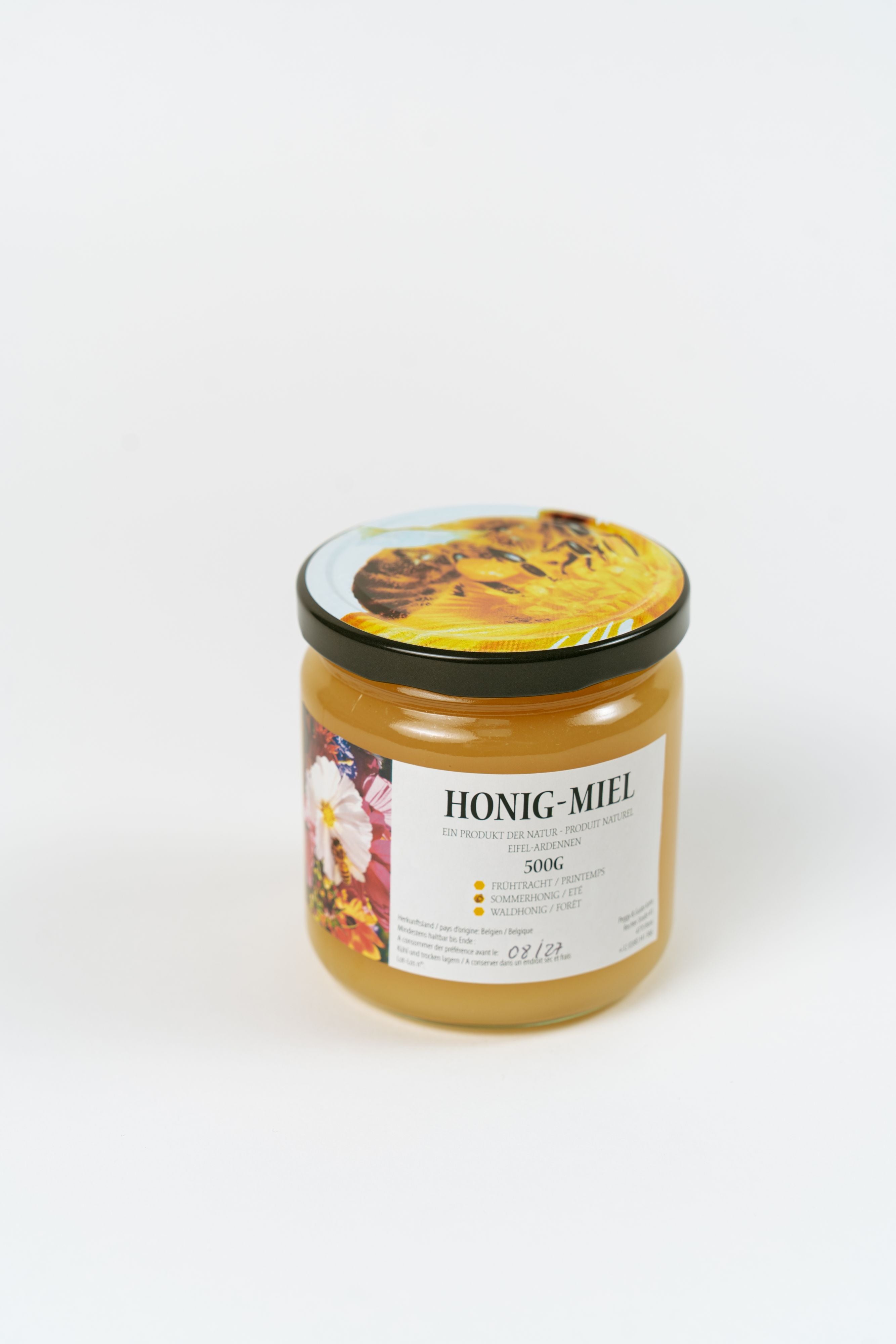 Pot de miel artisanal belge 500g avec couvercle illustré abeilles et vue inclinée