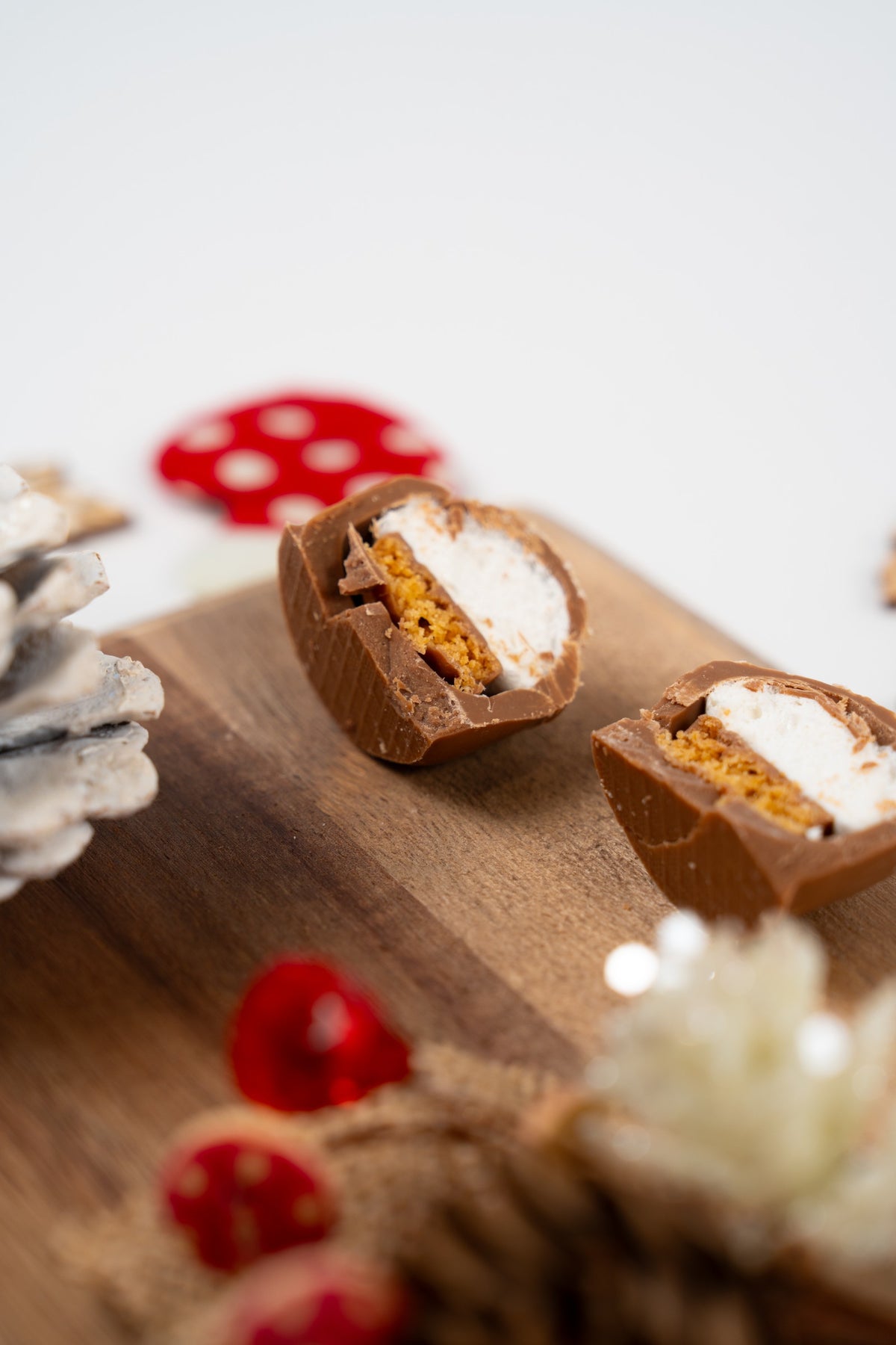 Mini Melocake Brésilienne au chocolat au lait coupé en deux, dévoilant une guimauve blanche et un cœur croustillant doré, présenté sur une planche en bois avec des décorations automnales.