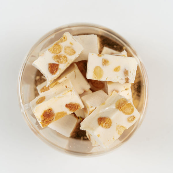 Morceaux de nougat aux amandes présentés dans une ambiance de confiserie artisanale et généreuse.