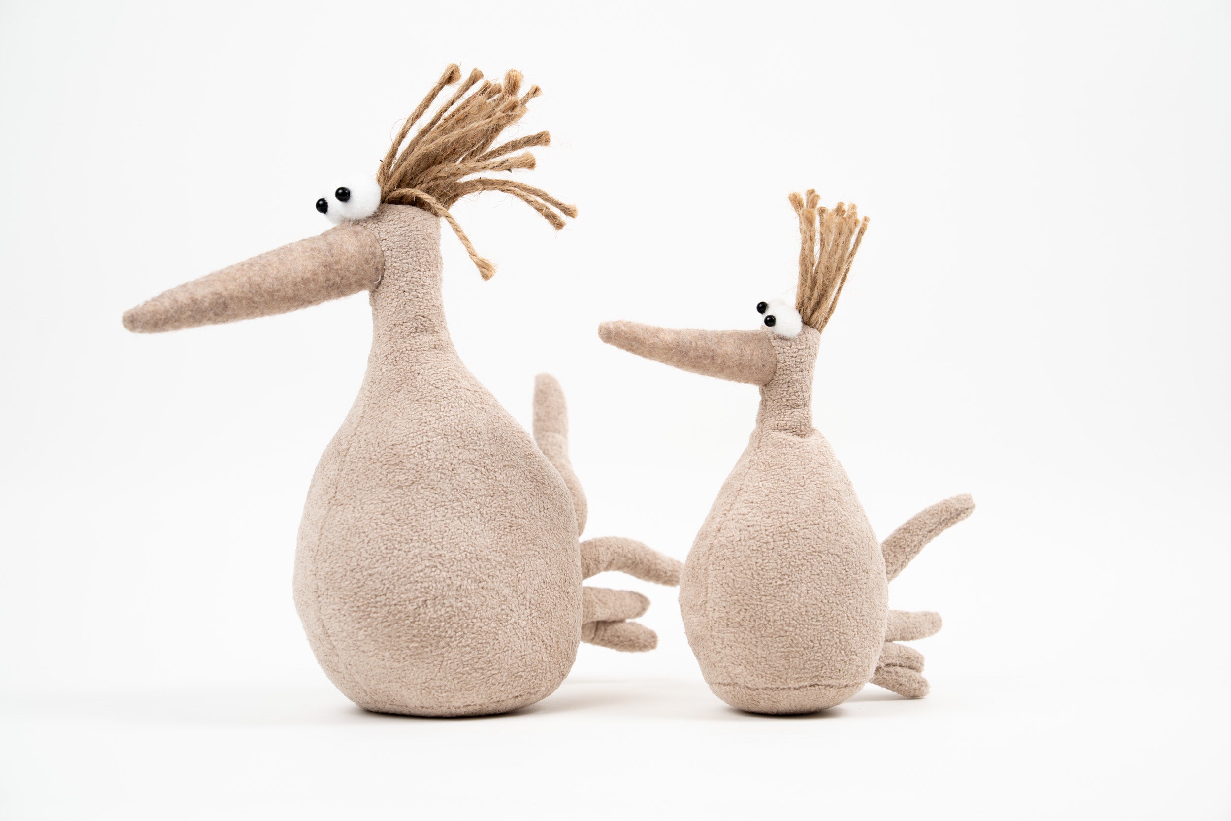 Pair of neutral fabric bird figures with long beaks and textured jute hair on a clean white background.