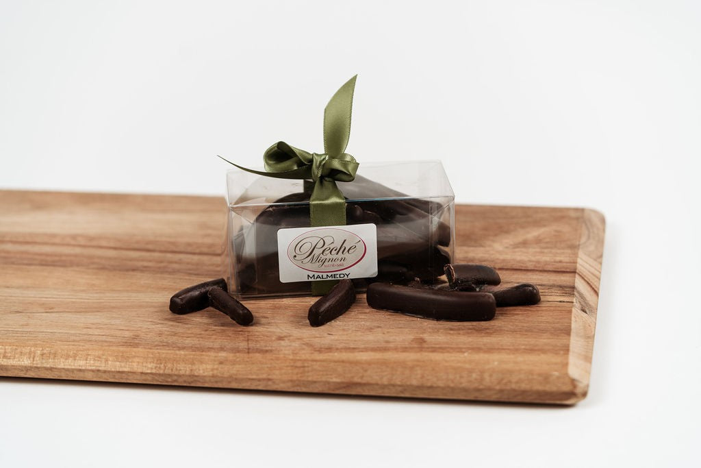 Orangettes artisanales enrobées de chocolat noir présentées dans un coffret transparent avec ruban sur planche en bois