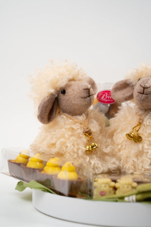 Gourmet Easter chocolate assortment with decorative lamb figures, pralines, and Easter chocolates on a gift platter.
