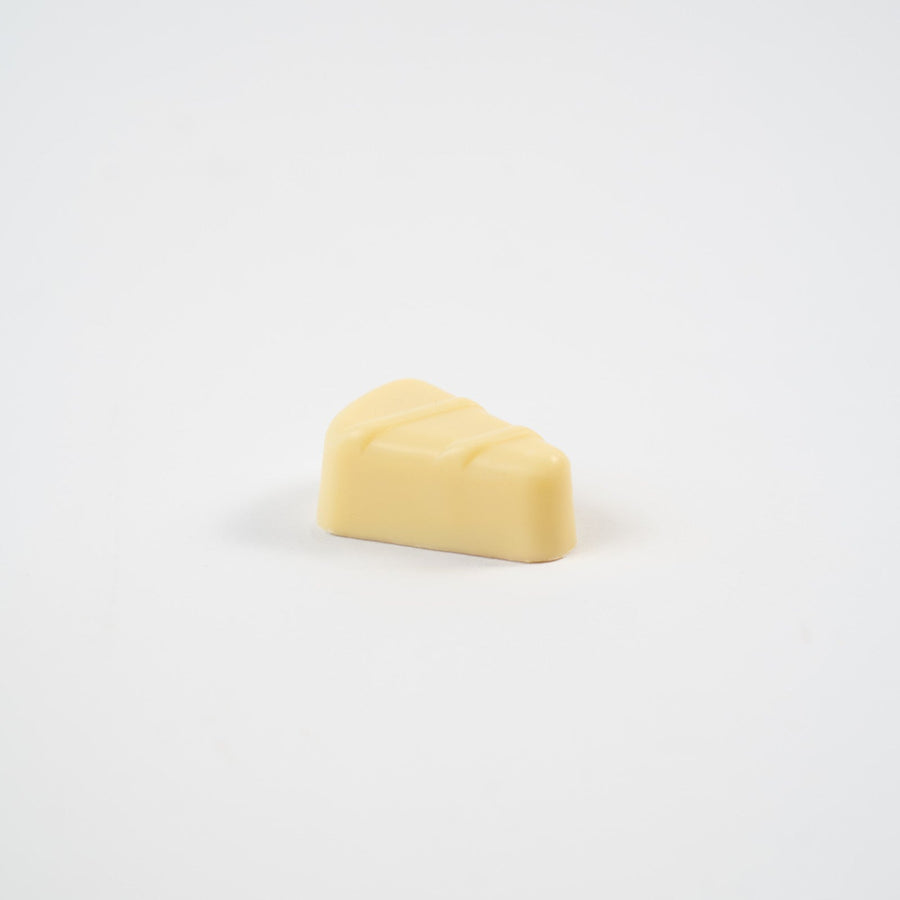 Artisan Belgian Banania praline in white chocolate with banana ganache, on a white background.