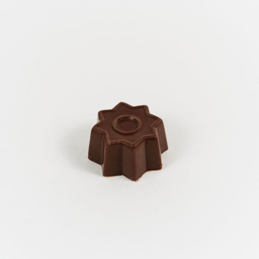 Artisan Belgian Étoile Caramel praline in milk chocolate with caramel ganache, on a white background.