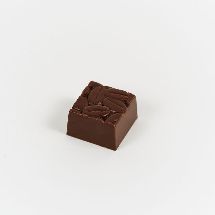 Artisan Belgian Énigme praline in milk chocolate with coffee cream, on a white background.