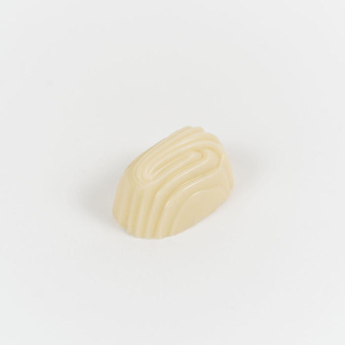 Artisan Belgian Gaëlle praline in white chocolate with crème brûlée filling, on a white background.
