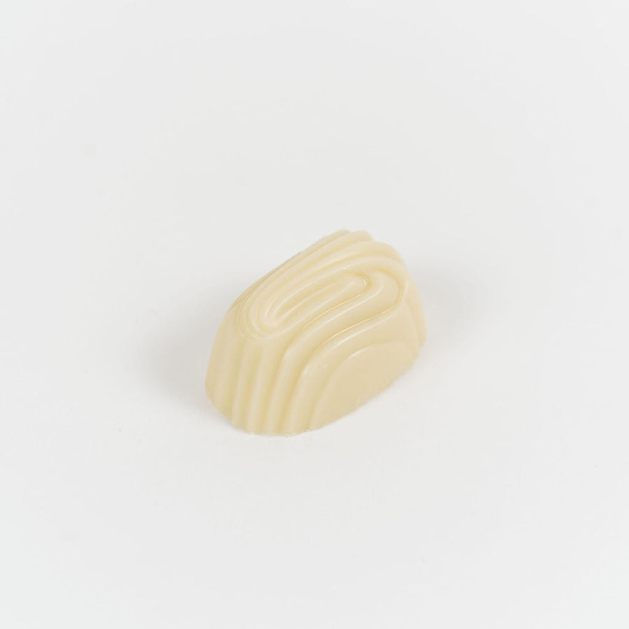 Artisan Belgian Gaëlle praline in white chocolate with crème brûlée filling, on a white background.