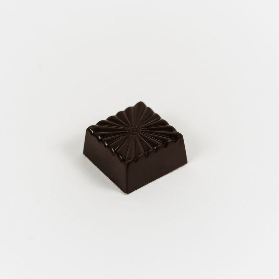 Artisan Belgian Koba praline in dark chocolate with house-made praline filling, on a white background.
