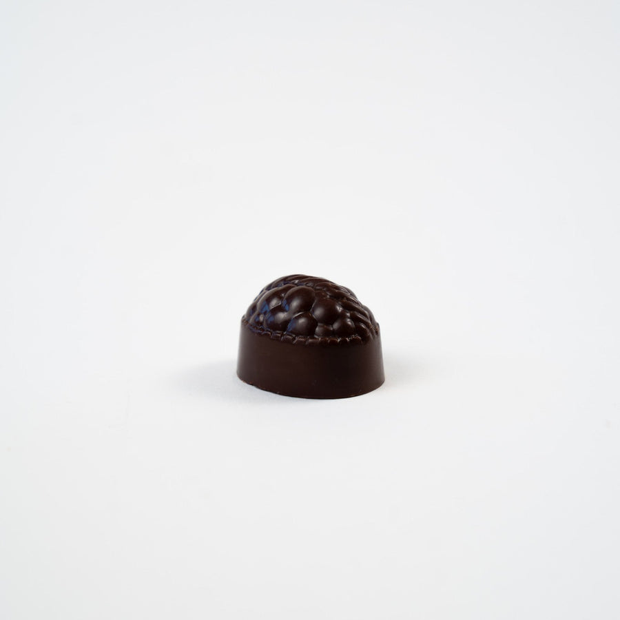 Artisan Belgian Lady praline in dark chocolate with raspberry fondant, on a white background.