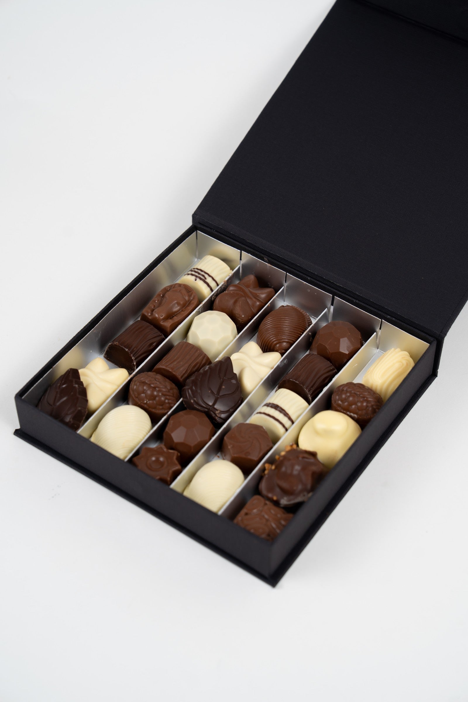 Pralines artisanales belges rectangulaires au décor blanc dans un coffret doré Péché Mignon