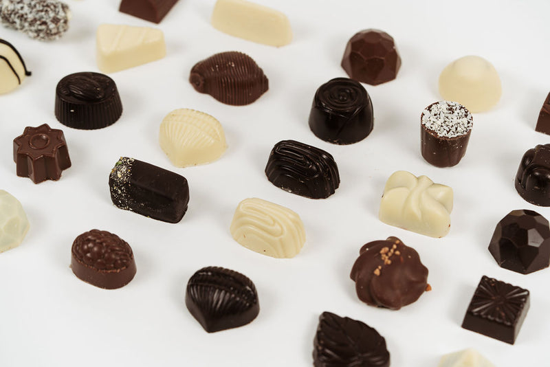 Assortiment de pralines belges au chocolat noir, lait et blanc sur fond clair