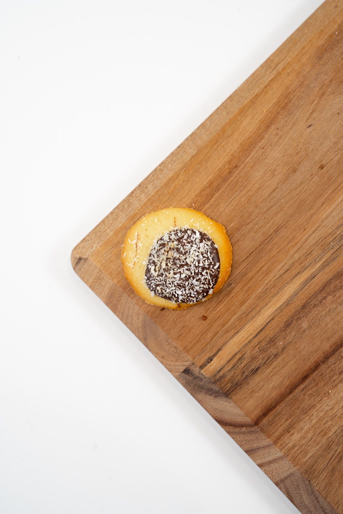 Biscuit Romia Coconut au cœur de chocolat et aux copeaux de noix de coco, présenté sur une planche en bois.
