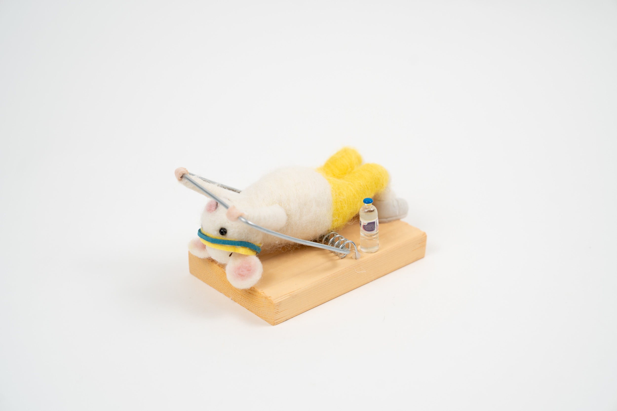Figurine La Souris Abdos en feutre vue de côté, avec barres d’exercice miniatures et petite bouteille sur socle en bois.