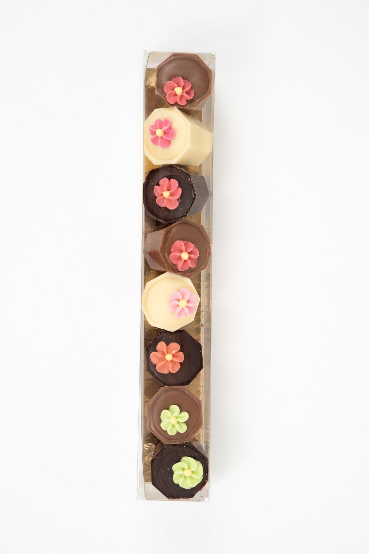 Top view of assorted TréZor chocolates with floral decoration in milk, dark and white chocolate in gift box