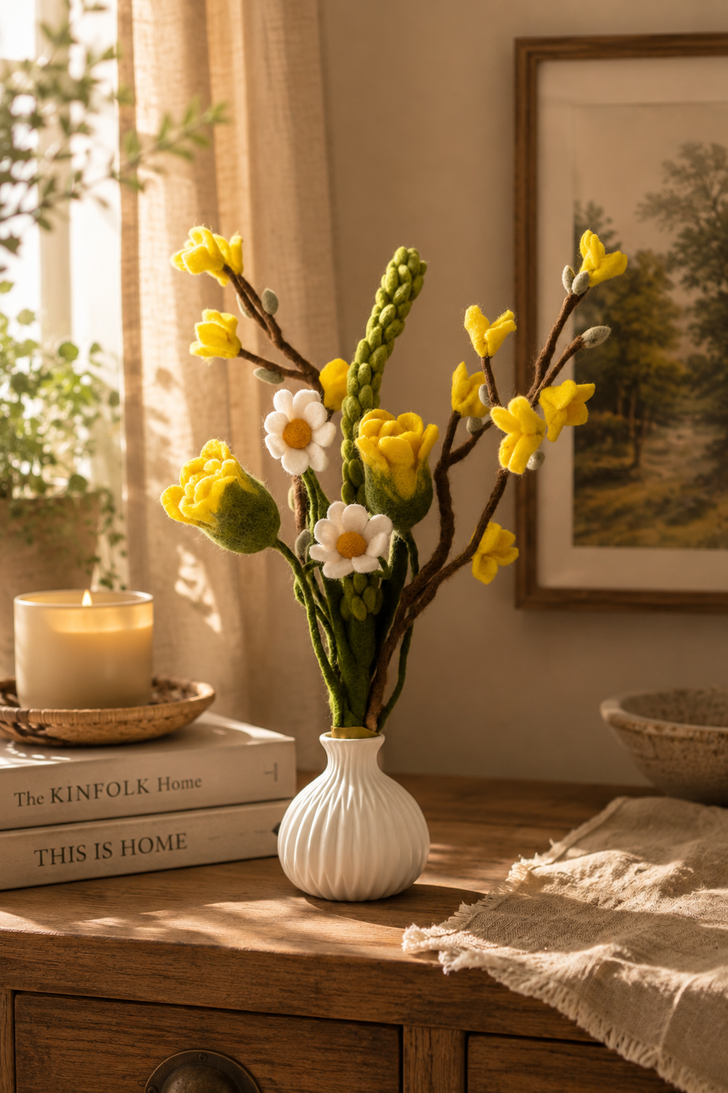 Yellow handmade felt flower arrangement in a white ceramic vase on a wooden table with warm sunlight and cosy home decor styling.
