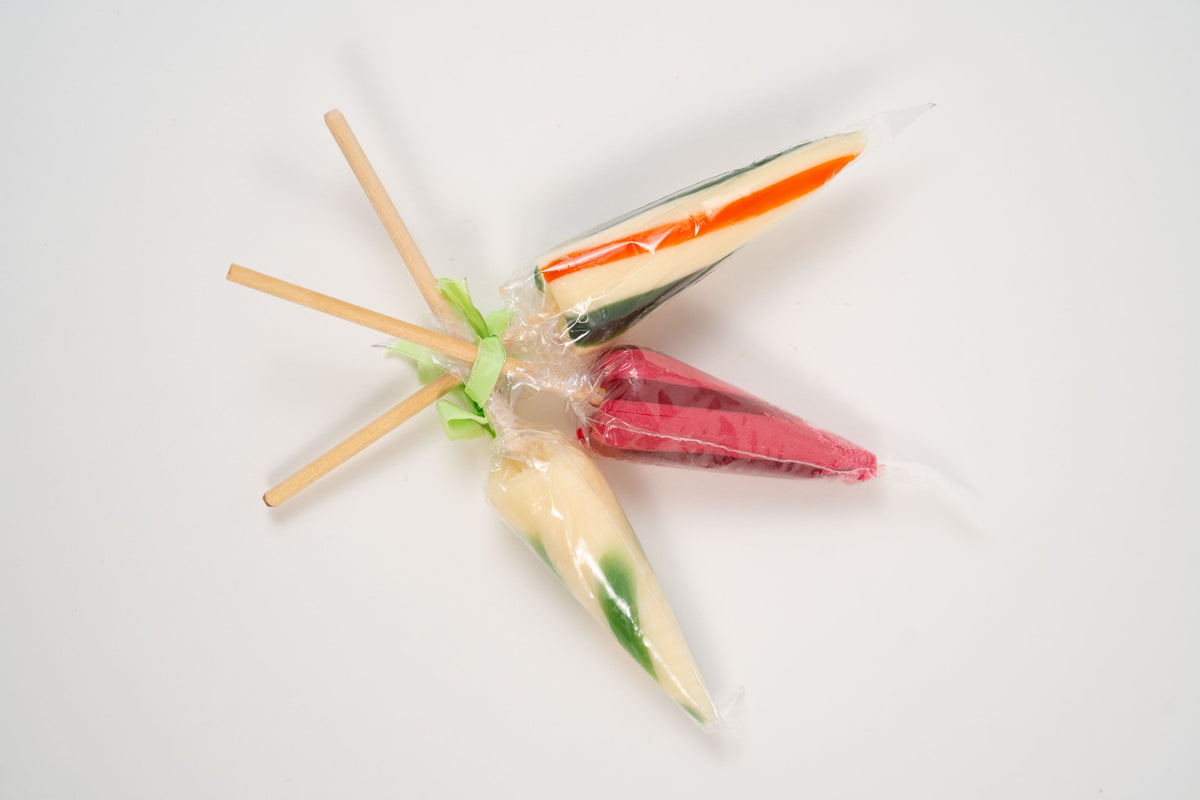 Gros plan sur une sucette parasol artisanale à la fleur de sureau, cadeau confiserie élégant.